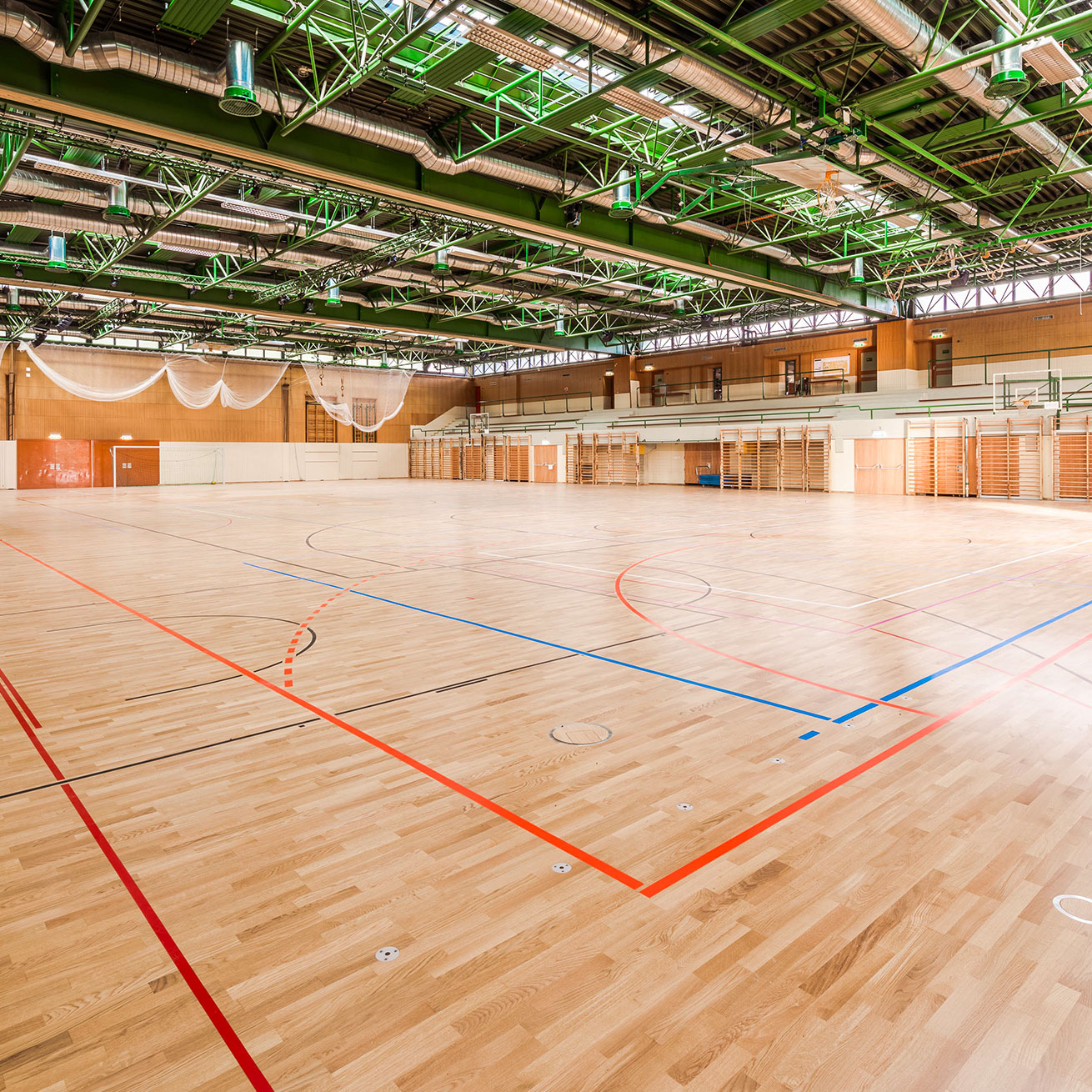 Bild zeigt große Turnhalle der Koralmhalle mit neu verlegtem Holzboden inklusive Bodenbeklebung.