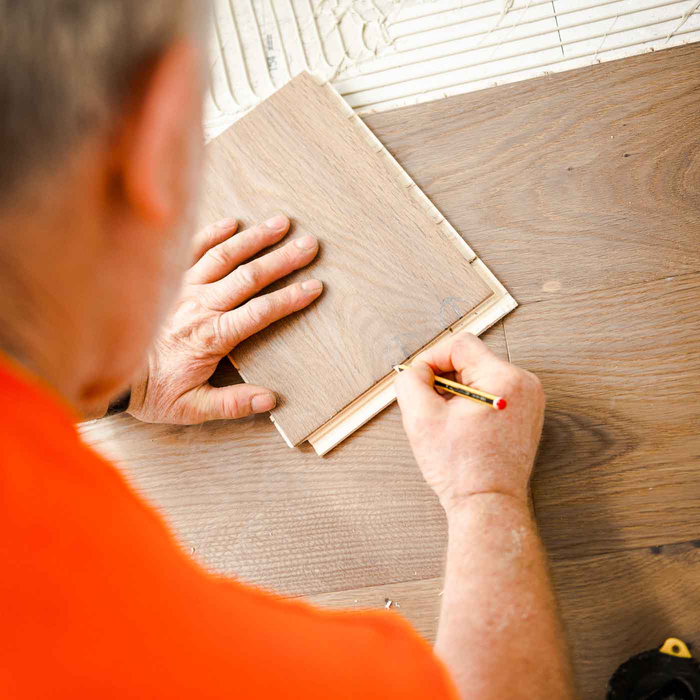Foto zeigt Detailfoto beim Einzeichnen von Abmessungen auf einem Holzboden.