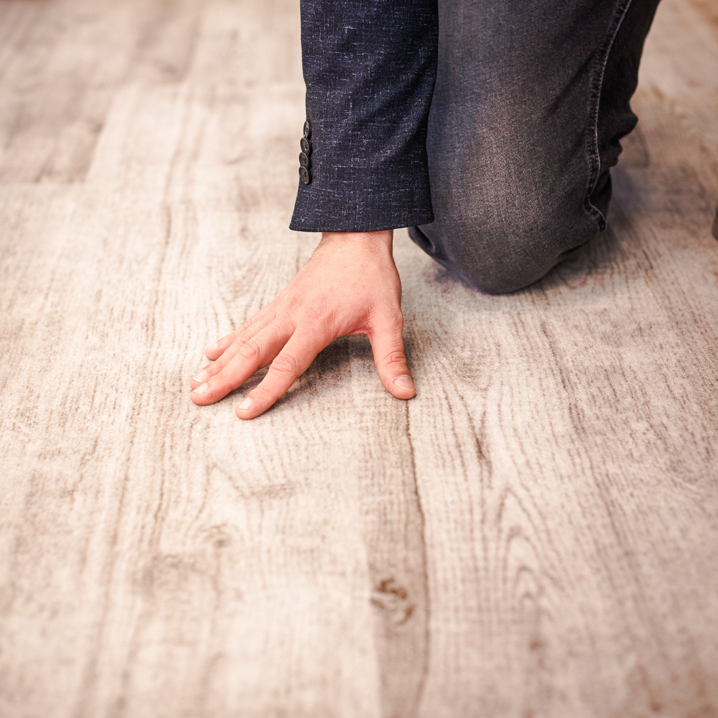 Bild zeigt Detail von Hand über einen neu verlegten Holzboden streichend.