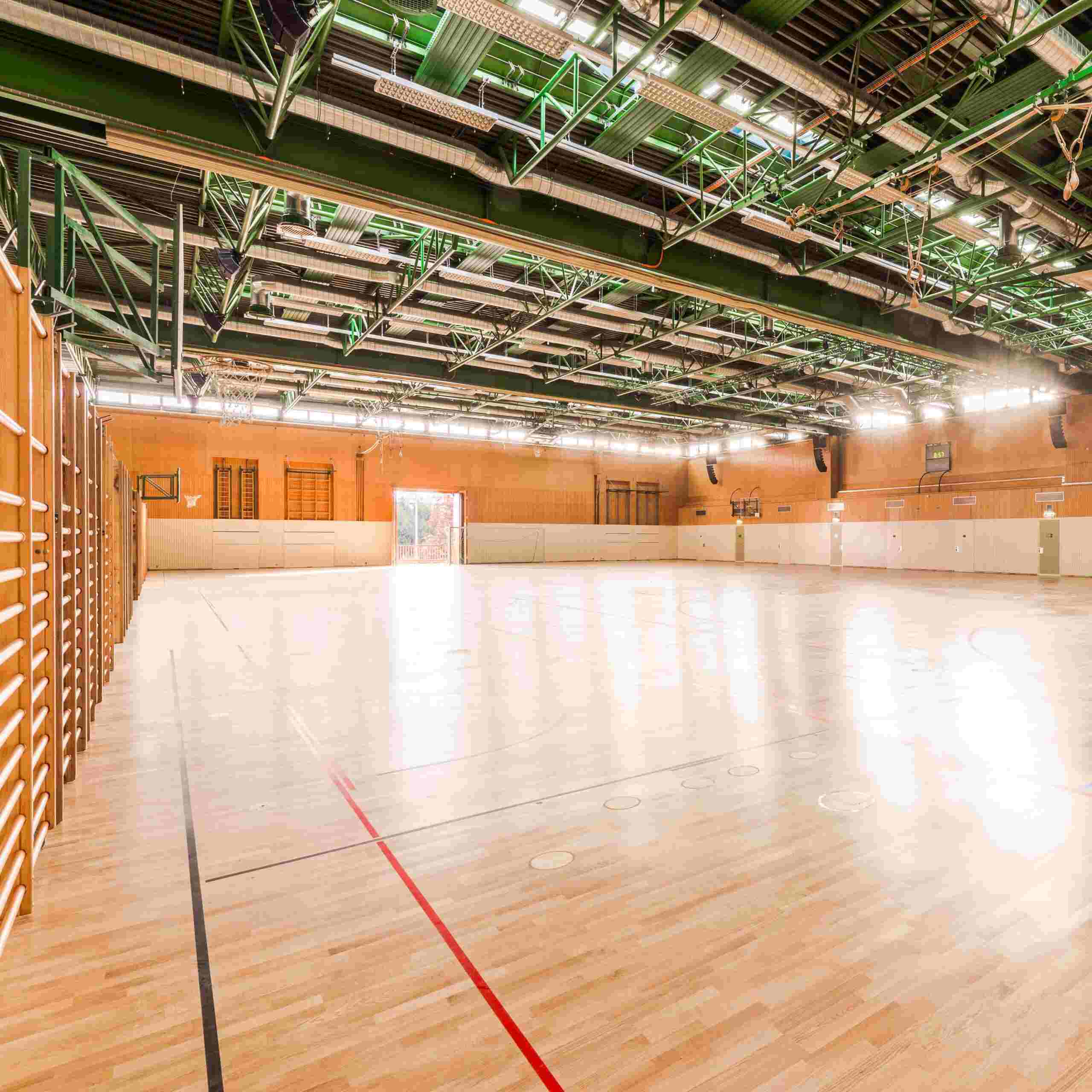 Bild zeigt große Turnhalle mit neu verlegtem Holzboden und Bodenbeklebung.