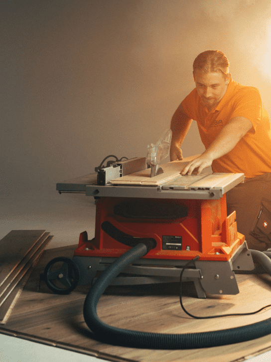 Bild zeigt einen ROBIA MItarbeiter bei Zuschneiden eines Holzboden in warmer Lichtatmosphäre.