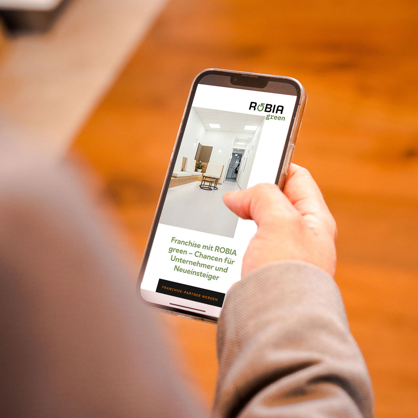 Ausschnitt zeigt Hand wie sie am Handy die ROBIA green Seite scrollt.