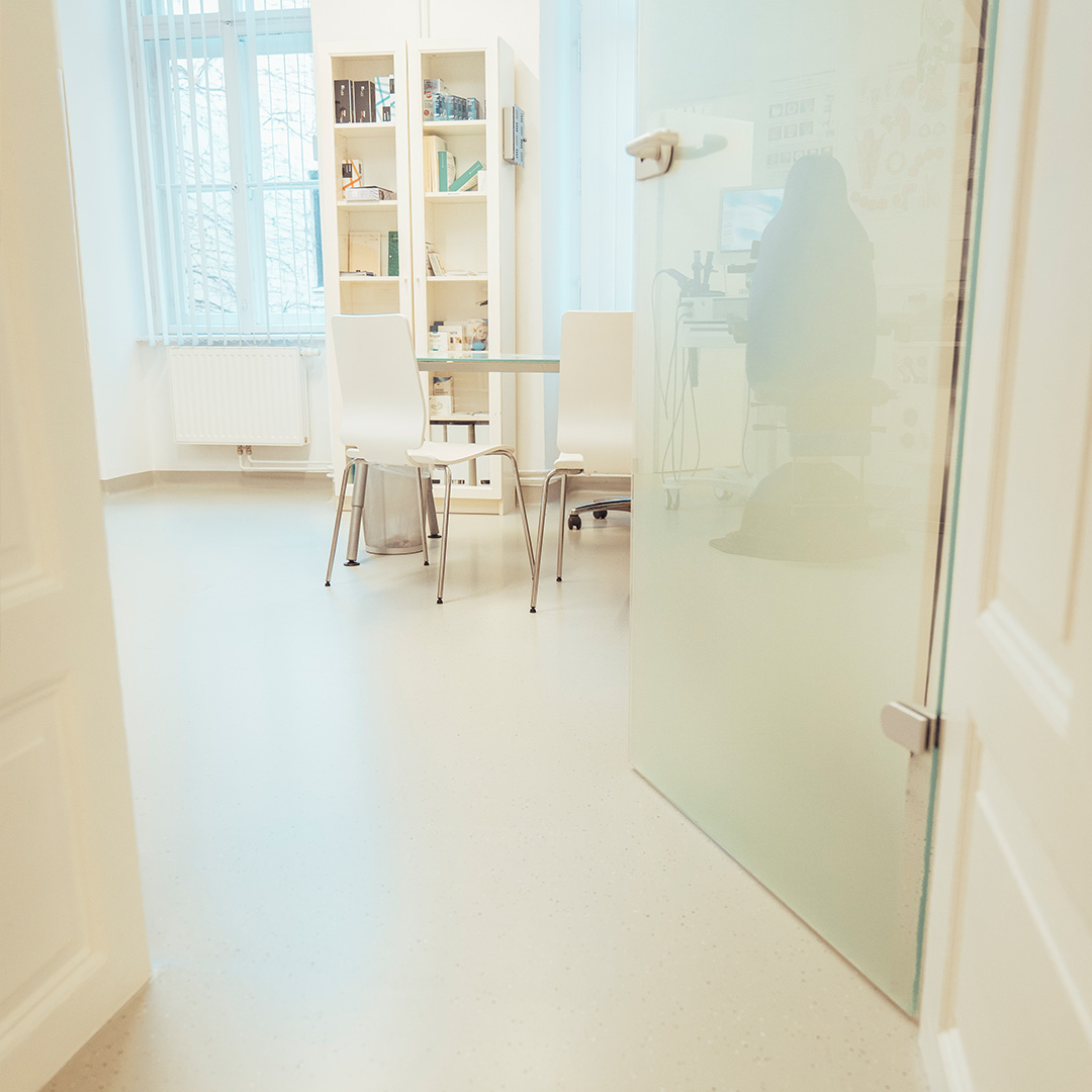 Bild zeigt antibakteriell sanierten hellen Kunststoffboden einer Internistin mit Blick auf das Behandlungszimmer.