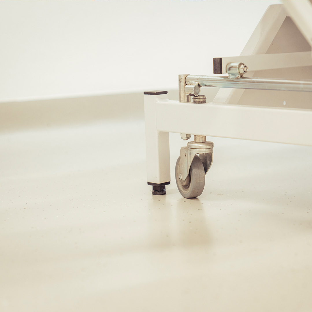 Bild zeigt sanierten hellen Kunststoffboden einer Arztpraxis mit Detail einer fahrbahren Liege.